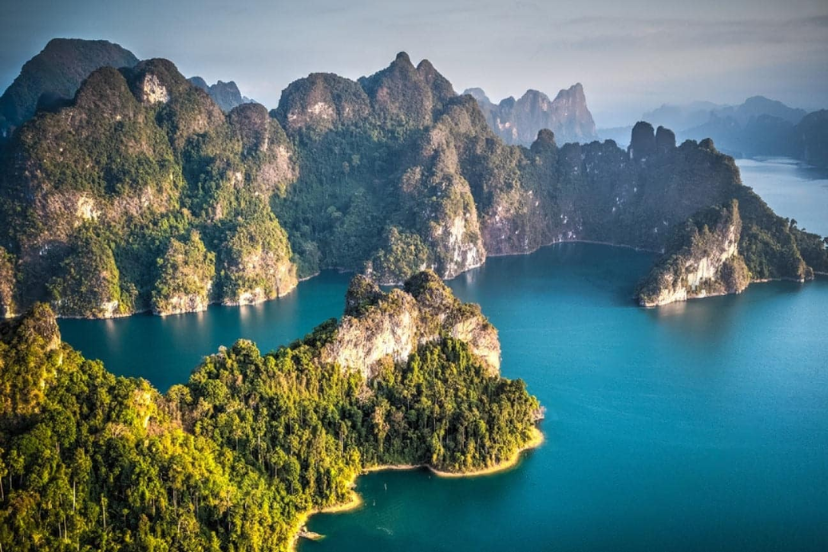 “Cheow Lan Lake with limestone cliffs reflected in jade-green water, Khao Sok, Thailand”