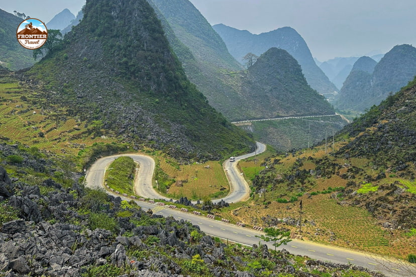 Aerial view of a winding mountain road in northern Vietnam, showcasing dramatic frontier landscapes and scenic curves ideal for big bike touring.