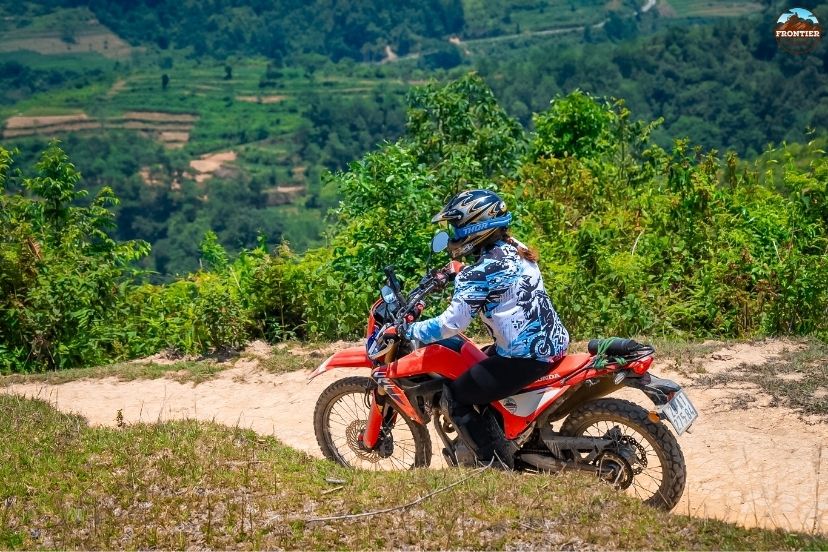 A reliable dual-sport motorcycle parked before a technical mountain track.